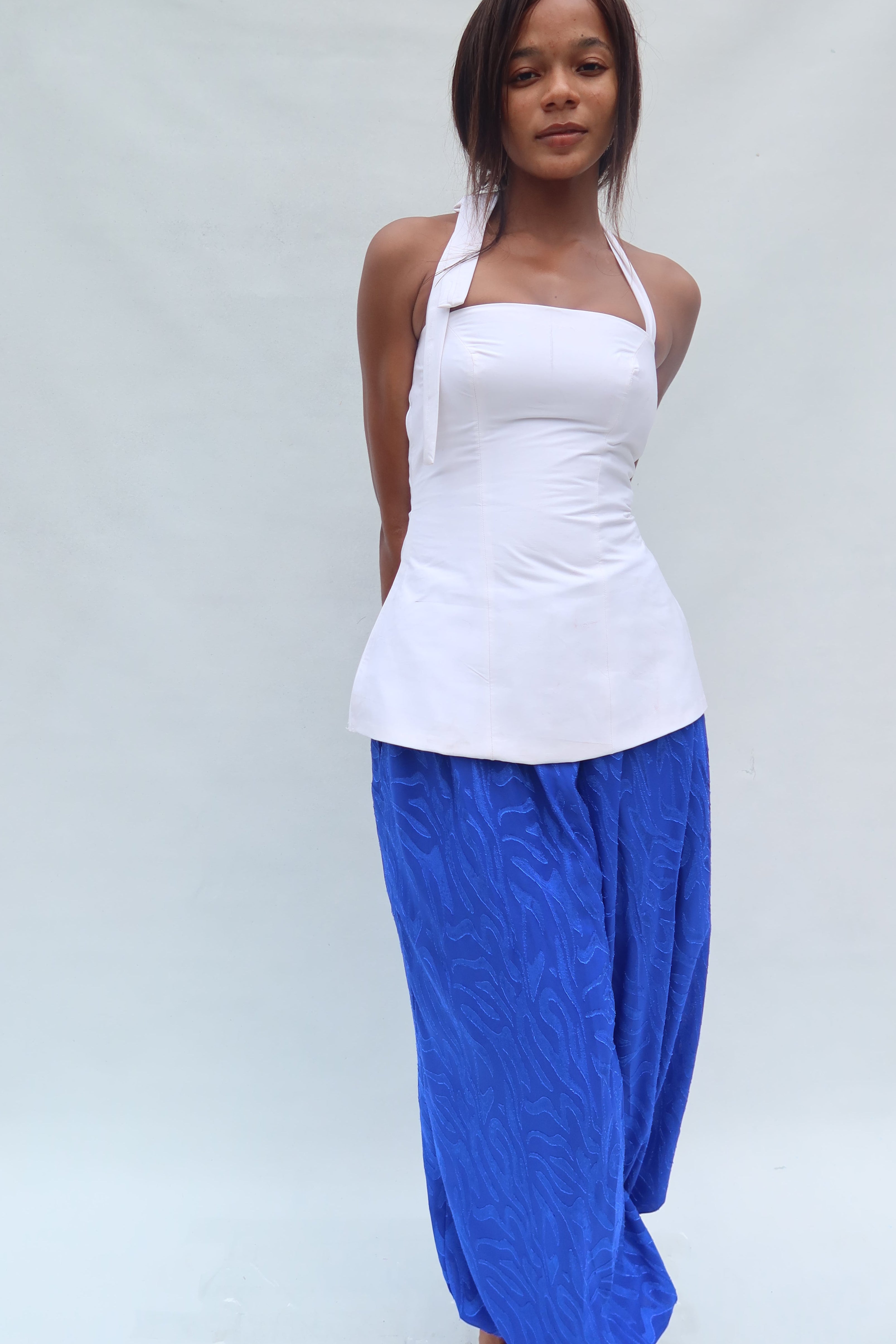 Person wearing a white top and blue pants on a light gray background